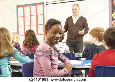 Stock Image - Schoolchildren Studying In Classroom With Teacher. Fotosearch