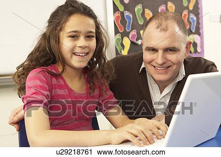 Stock Image - Schoolgirl In IT Class Using Computer With Teacher. Fotosearch