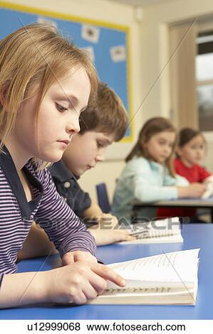 Stock Photo - Schoolgirl Reading Book In Classroom. Fotosearch
