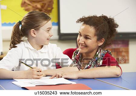 Stock Image - Schoolgirl Studying In Classroom With Teacher. Fotosearch