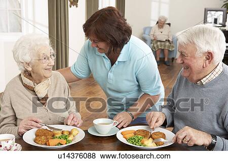 Stock Photo - Senior Couple Being Served Meal By Carer. Fotosearch