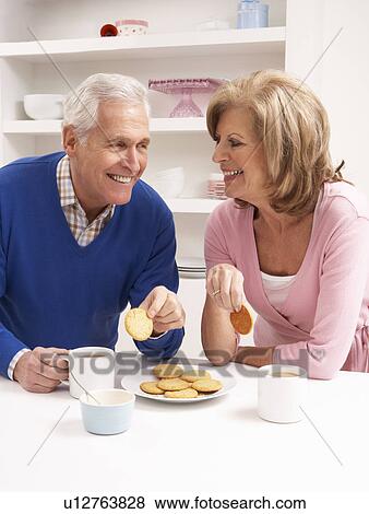 Stock Photo - Senior Couple Enjoying Hot Drink In Kitchen. Fotosearch