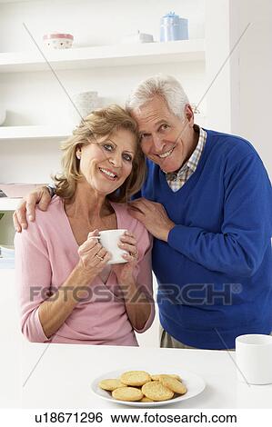 Stock Photograph - Senior Couple Enjoying Hot Drink In Kitchen. Fotosearch