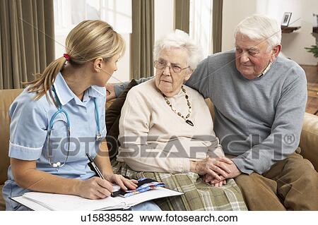 Stock Image - Senior Couple In Discussion With Health Visitor At Home. Fotosearch