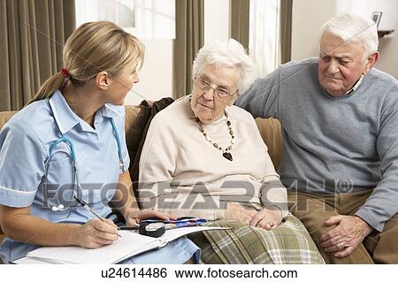 Stock Photograph - Senior Couple In Discussion With Health Visitor At Home. Fotosearch