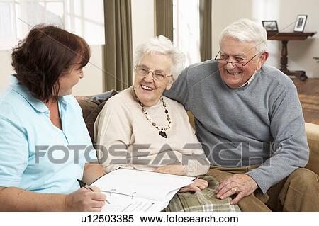 Stock Photography - Senior Couple In Discussion With Health Visitor At Home. Fotosearch