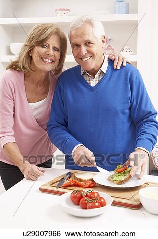 Stock Photograph - Senior Couple Making Sandwich In Kitchen. Fotosearch
