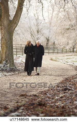 Stock Photography - Senior Couple On Winter Walk Through Frosty Landscape. Fotosearch