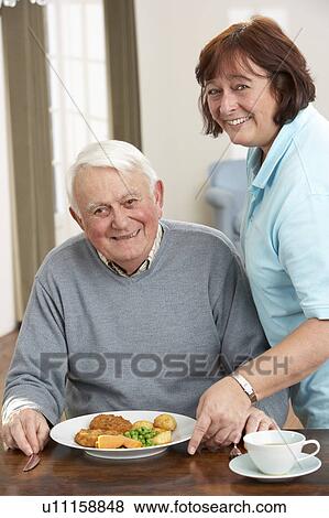 Stock Photo - Senior Man Being Served Meal By Carer. Fotosearch