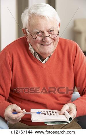 Senior Man Relaxing In Chair At Home Completing Crossword View Large Photo Image Picture - Senior Man Relaxing In Chair At Home Completing Crossword. Fotosearch