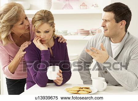 Stock Photography - Senior Mother Interferring With Couple Having Argument At Home. Fotosearch