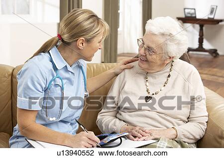 Stock Image - Senior Woman In Discussion With Health Visitor At Home. Fotosearch