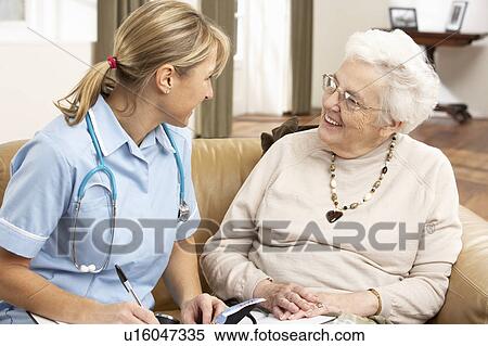 Stock Photography - Senior Woman In Discussion With Health Visitor At Home. Fotosearch
