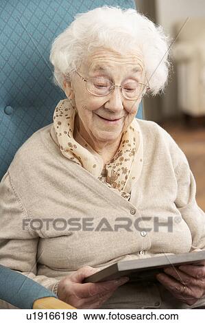 Stock Photo - Senior Woman Looking At Photograph In Frame. Fotosearch