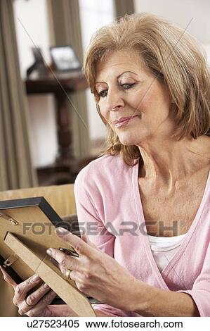 Stock Photography - Senior Woman Looking At Photograph In Frame. Fotosearch