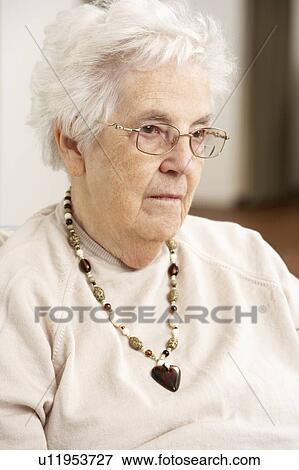 Stock Photo - Senior Woman Looking Sad In Chair At Home. Fotosearch