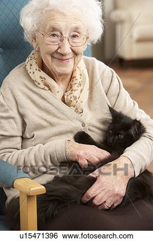 Stock Photograph - Senior Woman Relaxing In Chair At Home With Pet Cat. Fotosearch