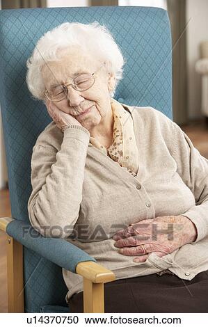 Stock Image - Senior Woman Resting In Chair At Home. Fotosearch