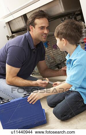 Picture - Son Helping Father To Mend Sink In Kitchen. Fotosearch