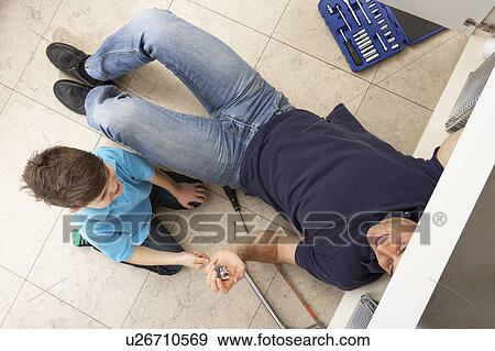 Stock Photo - Son Helping Father To Mend Sink In Kitchen. Fotosearch