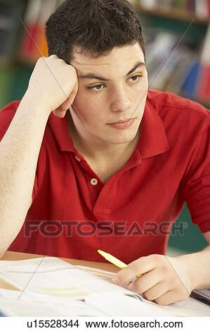 Picture - Stressed Male Teenage Student Studying In Classroom. Fotosearch