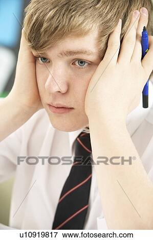 Stock Photo - Stressed Male Teenage Student Studying In Classroom. Fotosearch