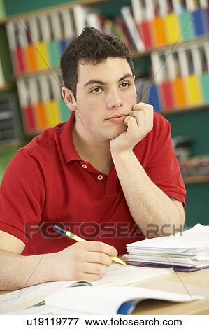 Stock Photo - Stressed Male Teenage Student Studying In Classroom. Fotosearch