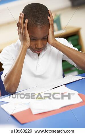 Stock Photo - Stressed Schoolboy Studying In Classroom. Fotosearch