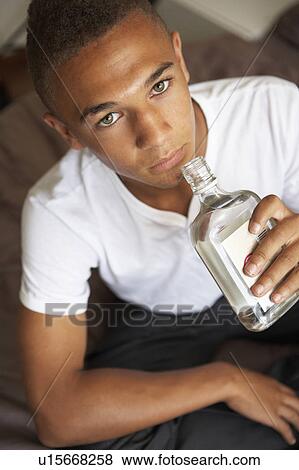 Stock Photo - Teenage Boy Lying In Bedroom Drinking. Fotosearch