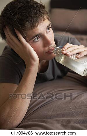 Stock Photograph - Teenage Boy Lying In Bedroom Drinking. Fotosearch