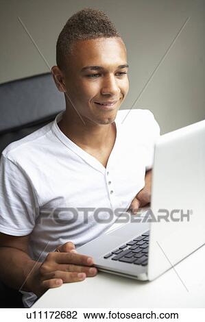 Stock Image - Teenage Boy Using Laptop At Home. Fotosearch
