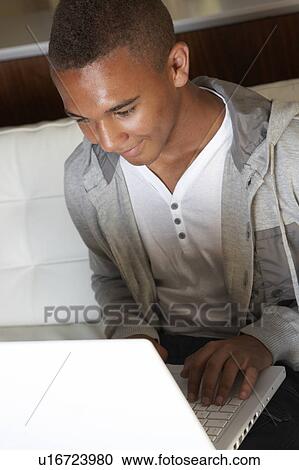Stock Image - Teenage Boy Using Laptop At Home. Fotosearch