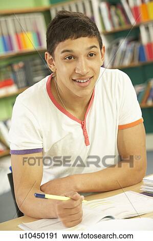 Stock Image - Teenage Male Student In Working In Classroom. Fotosearch