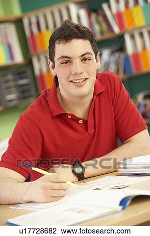 Stock Image - Teenage Male Student In Working In Classroom. Fotosearch