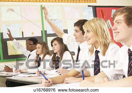 Stock Photograph - Teenage Student Answering Question Studying In Classroom. Fotosearch