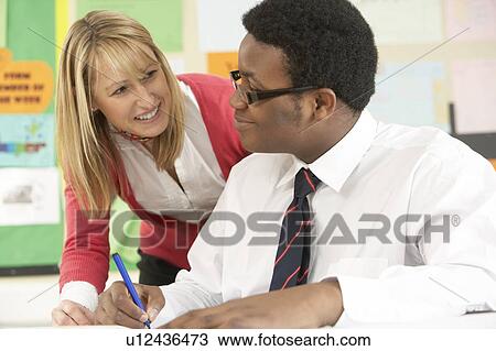 Stock Image - Teenage Student Working In Classroom With Teacher. Fotosearch