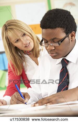 Stock Photo - Teenage Student Working In Classroom With Teacher. Fotosearch