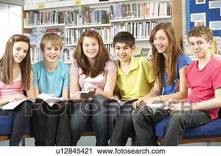 Stock Image - Teenage Students In Library Reading Books. Fotosearch