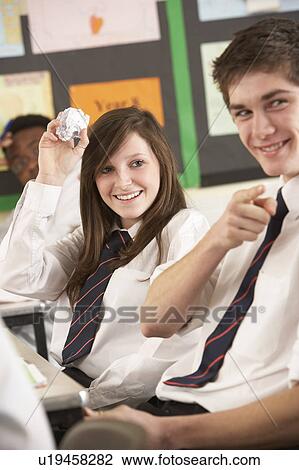 Stock Image - Teenage Students Misbehaving In Classroom. Fotosearch