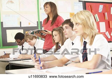 Stock Image - Teenage Students Studying In Classroom With Teacher. Fotosearch