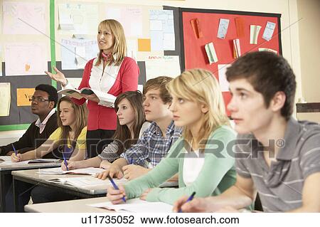 Stock Image - Teenage Students Studying In Classroom With Teacher. Fotosearch
