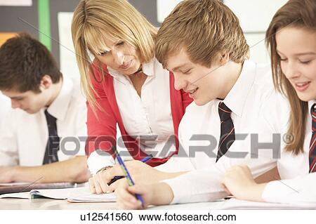 Stock Image - Teenage Students Studying In Classroom With Teacher. Fotosearch