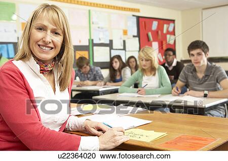Stock Image - Teenage Students Studying In Classroom With Teacher. Fotosearch