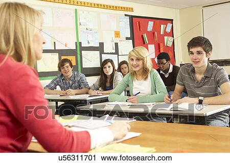 Stock Image - Teenage Students Studying In Classroom With Teacher. Fotosearch