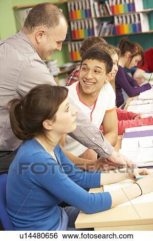 Stock Photograph - Teenage Students Studying In Classroom With Tutor. Fotosearch