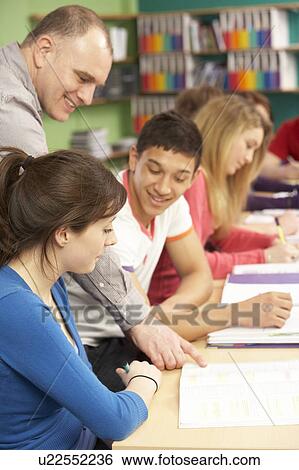 Stock Photograph - Teenage Students Studying In Classroom With Tutor. Fotosearch