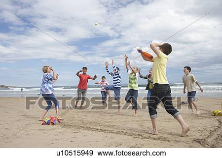 Stock Photo - Teenagers playing baseball on beach. Fotosearch