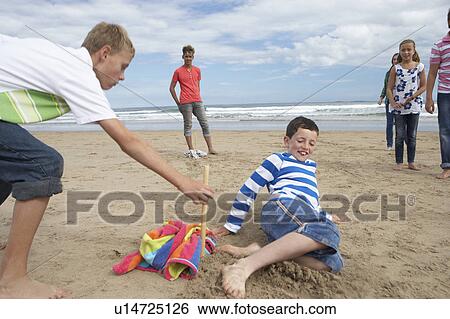 Stock Photograph - Teenagers playing baseball on beach. Fotosearch