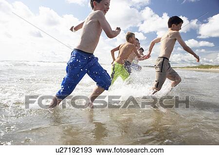 Stock Image - Teenagers playing on beach. Fotosearch
