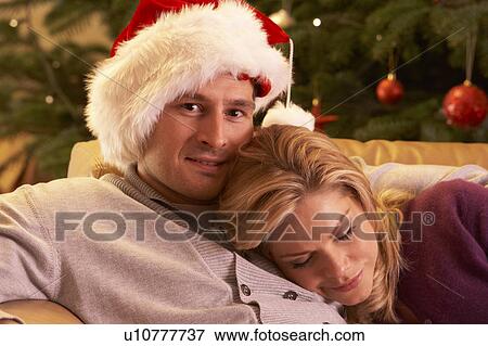Stock Photo - Tired Couple Relaxing In Front Of Christmas Tree. Fotosearch